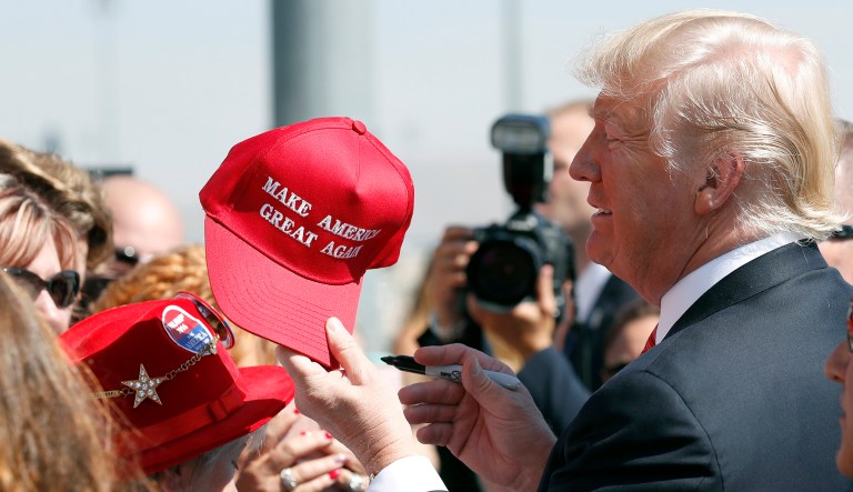 In this Aug. 23, 2017 file photo, President Trump hands a signed "Make America Great Again," hat back to a supporter in Reno, Nev. 