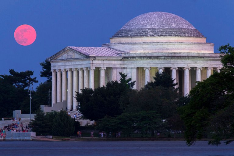 The full moon appears red as it burns through the haze as it rises behind the Jefferson Memorial in Washington.