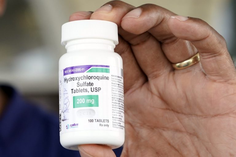 Dr. Robin Armstrong holds a bottle of hydroxychloroquine while posing outside The Resort at Texas City nursing home, where he is the medical director. A new survey shows that the drug has become politicized.