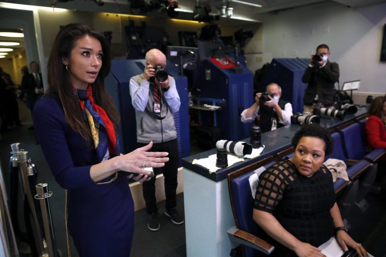 PBS reporter Yamiche Alcindor, seated, watches as One America News White House Correspondent Chanel Rion asks a question of President Donald Trump during a briefing. Photographer Doug Mills is standing at left. Mills and Alcindor won awards from the White House Correspondents' Association.