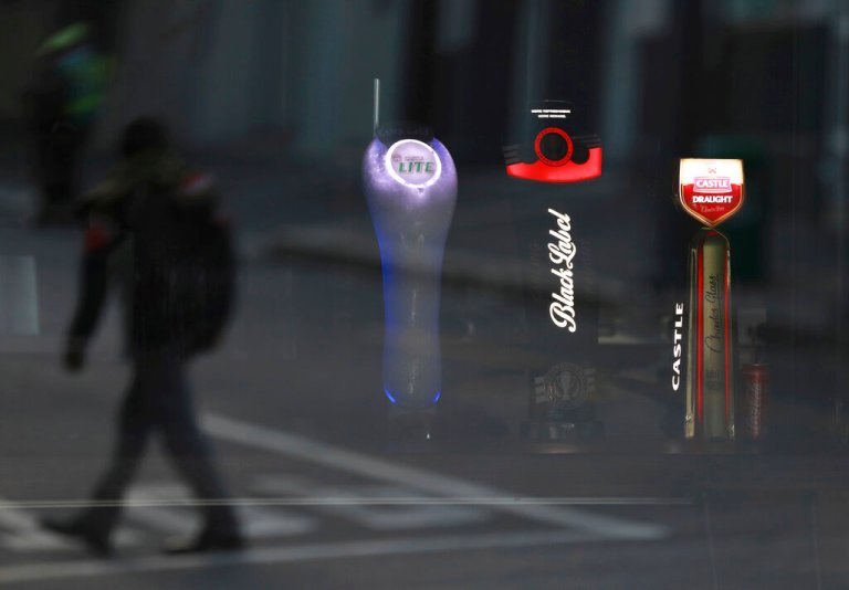 FILE - In this May 7, 2020, file photo, beer taps of South African Brewery brands are seen through the window of a closed bar in Cape Town, South Africa. A bootlegging culture has sprung up across South Africa in response to the government's nearly 8-week-old ban on the sale of cigarettes and alcohol.
