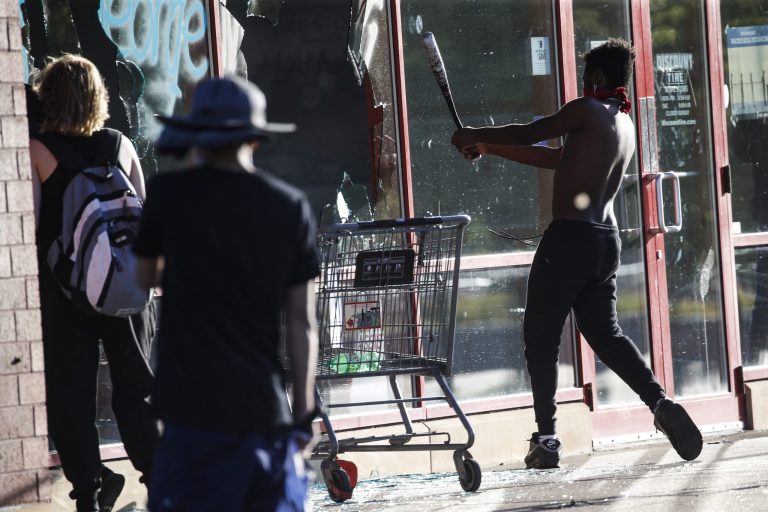A protestor breaks a window of a business with a baseball bat, in St. Paul, Minn. last month. The destruction caused by vandals and looters in cities across the country, who struck as demonstrators took to the streets in reaction to the killing of George Floyd in Minneapolis, has devastated small businesses already reeling from the coronavirus outbreak.