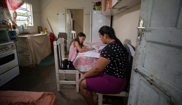 Amanda Trindade helps her 9-year-old daughter Giovana with her homework that was dropped off by a school worker at their home in the rural area in Sao Jose dos Campos, Brazil, Tuesday, July 14, 2020. In March when schools closed due to the COVID-19 pandemic, the Mother Teresa school decided to deliver homework to students because most of them don't have computers or have very limited Internet access.
