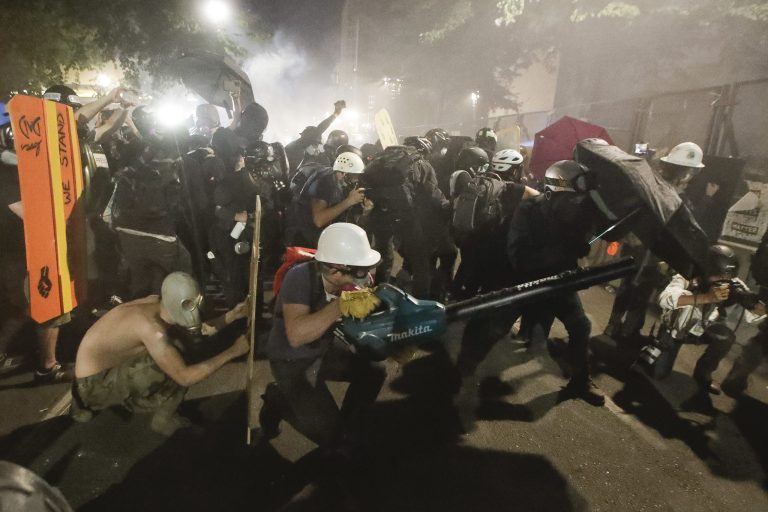 Demonstrators huddle and blow back tear gas with leaf blowers during clashes with federal officers during a Black Lives Matter protest at the Mark O. Hatfield United States Courthouse Wednesday in Portland, Ore.