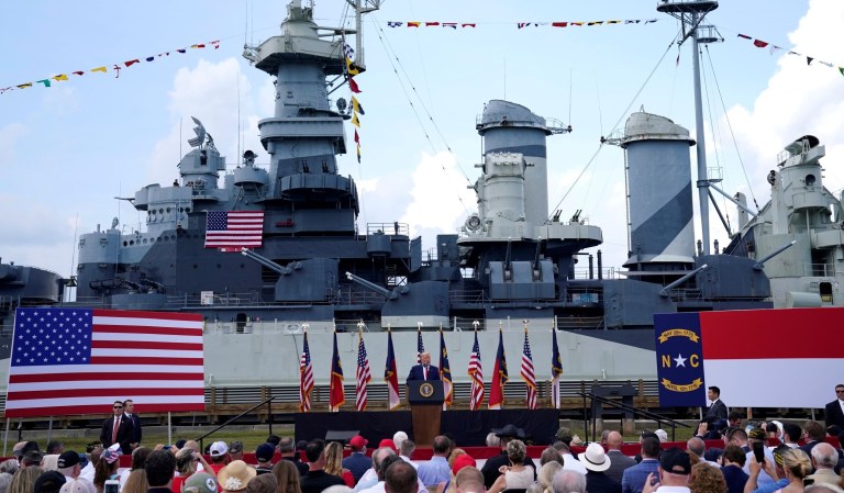 With the the Battleship North Carolina in the background, President Donald Trump speaks during an event to designate Wilmington as the first American World War II Heritage City in Wilmington, N.C.