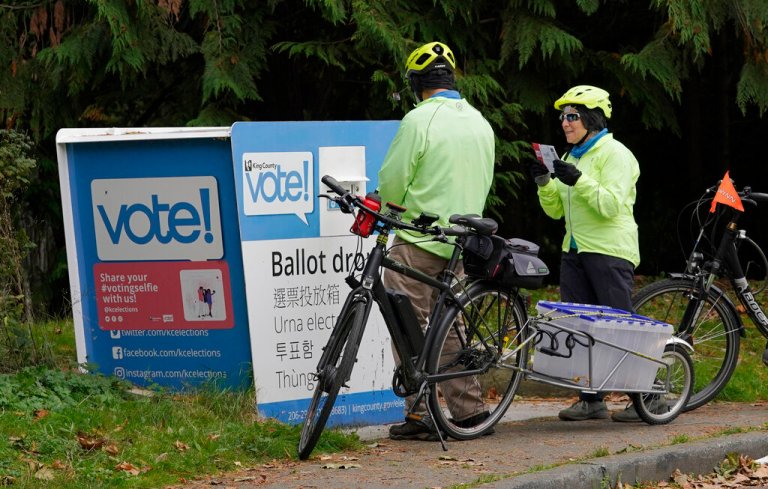 No ID required. A person who declined to give a name pauses to kiss their ballot before depositing it in an outdoor ballot drop box, Friday, Oct. 16, 2020, near Gas Works Park in Seattle. Washington is a vote-by-mail state, but ballots can also be deposited at drop boxes, which opened this week in the Seattle area.