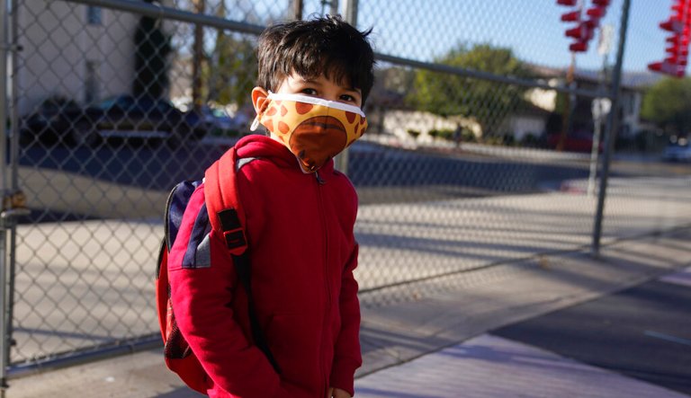 A students wears a mask while arriving at Newhall Elementary School Thursday, Feb. 25, 2021, in Santa Clarita, Calif. Elementary school students returned to school this week in the Newhall School District.