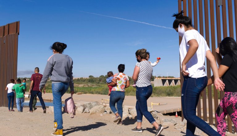This Tuesday, June 8, 2021, photo shows a group of Brazilian immigrants making their way around a gap in the U.S.-Mexico border in Yuma, Arizona, seeking asylum in the United States after crossing over from Mexico. 