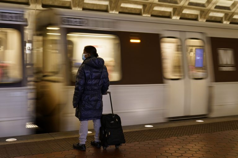 FILE - A woman waits to board a train as it arrives at Metro Center station on April 23, 2021, in Washington.
