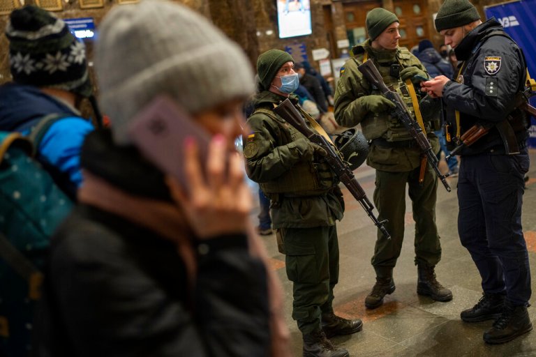 Ukrainian soldiers stand guard as people try to leave at the Kyiv train station in Ukraine on Thursday.