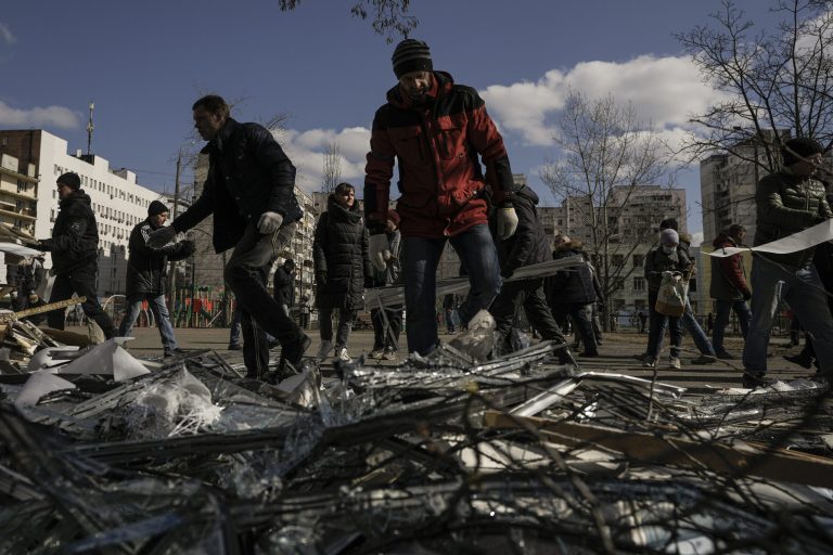 Russian troops cleaning up bombed-out Mariupol theater for parade, Ukraine says People clear debris outside a medical center damaged after parts of a Russian missile, shot down by Ukrainian air defense, landed on a nearby apartment block, according to authorities, in Kyiv, Ukraine, on Thursday.