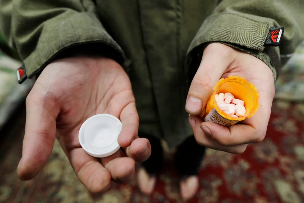FILE - In this Nov. 14, 2019, photo, Jon Combes holds his bottle of buprenorphine, a medicine that prevents withdrawal sickness in people trying to stop using opiates, as he prepares to take a dose in a clinic in Olympia, Wash. The U.S. Department of Justice made clear, Tuesday, April 2, 2022, that barring the use of medication treatment for opioid abuse is a violation of federal law.