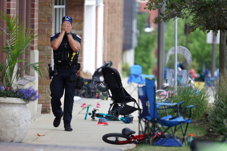 A Lake Forest, Illinois, police officer walks down Central Ave in Highland Park, Illinois, on Monday, July 4, 2022, after a shooter fired on the northern suburb's Fourth of July parade.