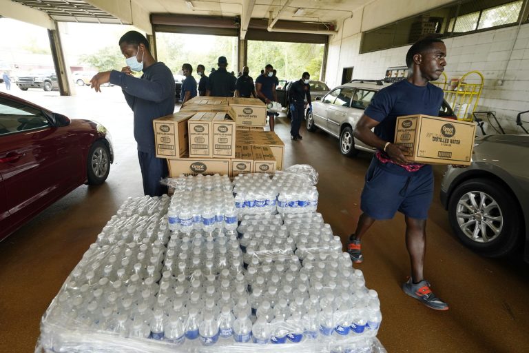 Firefighters and recruits for the Jackson, Mississippi, Fire Department carry cases of bottled water to residents' vehicles on Aug. 18, 2022, as part of the city's response to long-standing water system problems. On Monday, Aug. 29, 2022, Mississippi Gov. Tate Reeves said he's declaring a state of emergency after excessive rainfall worsened problems in one of Jacksonâs already troubled water-treatment plants. 