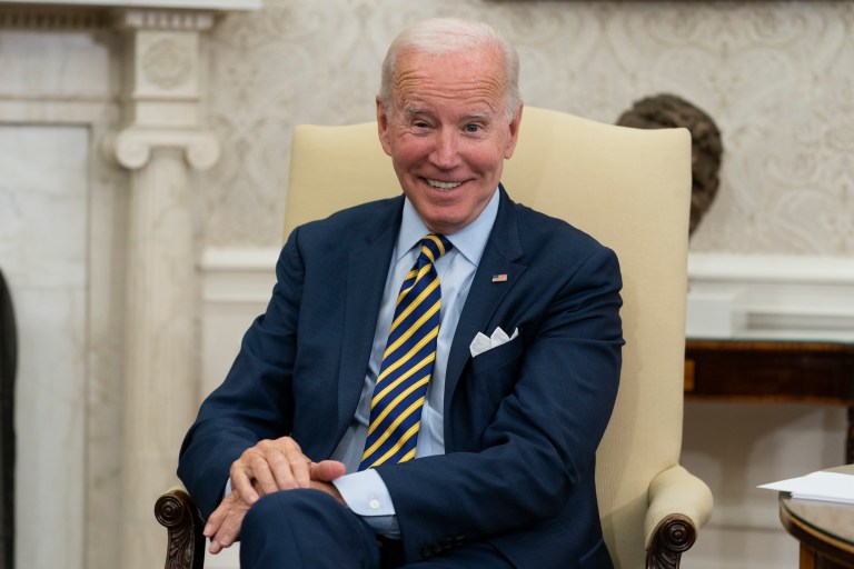 President Joe Biden smiles in the Oval Office.