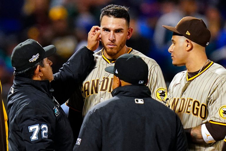 Umpire Alfonso Marquez (72) checks for substances behind the ears of San Diego Padres starting pitcher Joe Musgrove (44) during the sixth inning of Game 3 of a National League wild-card baseball playoff series against the New York Mets, Sunday, Oct. 9, 2022, in New York. 