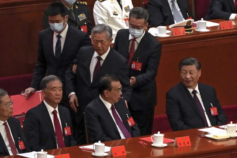 Chinese President Xi Jinping (right) looks on as former Chinese President Hu Jintao (standing at center) touches the shoulder of Premier Li Keqiang as he is assisted to leave the hall during the closing ceremony of the 20th National Congress of China's ruling Communist Party in Beijing on Saturday.
