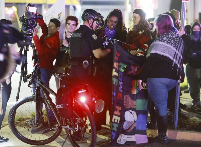 A police officer talks to protesters outside Plaza Live where âA Drag Queen Christmasâ took place in Orlando, Florida, on Wednesday, Dec. 28, 2022. According to a tweet from the press secretary for Gov. Ron DeSantis, the show has triggered a state investigation. 