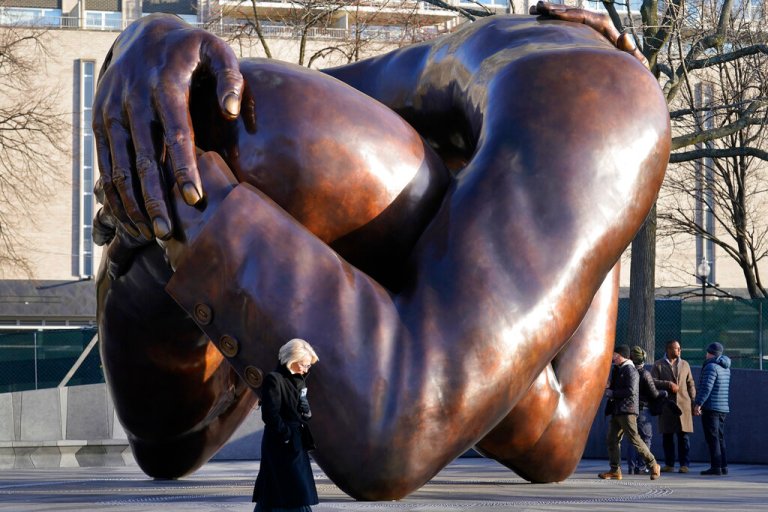 Passers-by walk near the 20-foot-high bronze sculpture 