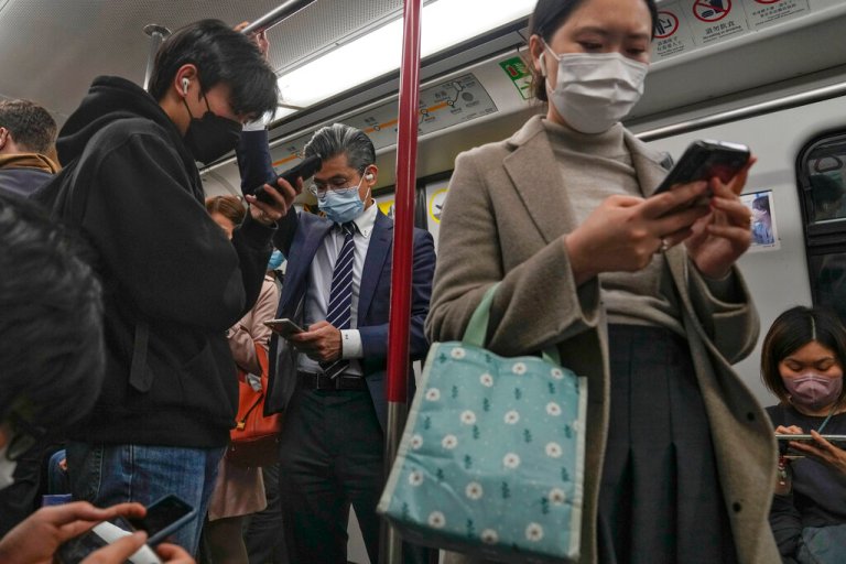 Commuters wearing face masks browse their smartphones as they ride on a subway train in Hong Kong on Feb. 7, 2023. Hong Kong will lift its mask mandate Wednesday, March 1, 2023, ending the cityâs last major restriction imposed during the COVID-19 pandemic. 