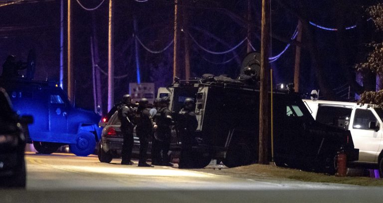 KCPD SWAT officers stand behind a Bearcat tactical vehicle during a standoff on Tuesday, Feb. 28, 2023, in Kansas City, Missouri. 