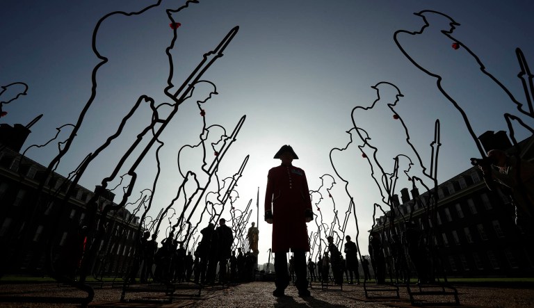 A Chelsea Pensioner, in his ceremonial uniform as a retired member of the British army and resident of the Royal Hospital Chelsea retirement and care home, poses for photographs with 6 foot 'Tommy' figures at the Royal Hospital Chelsea in London, for the 'There But Not There' campaign to commemorate the upcoming centenary of the end of World War I, Tuesday, Oct. 16, 2018. 