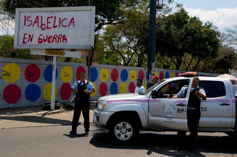 In this photo taken on Saturday, March 15, 2014. Carabobo's State police officers stand next to graffiti that reads in Spanish 