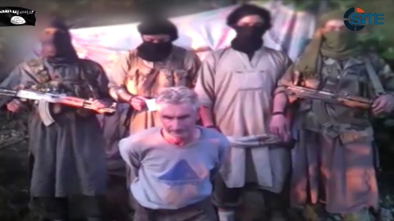 Members of a group calling itself Jund al-Khilafah, or Soldiers of the Caliphate, stand behind French mountaineer Herve Gourdel just before beheading him. In the video, the men pledge their allegiance to the leader of the Islamic State group, Abu Bakr al-Baghdadi, before killing Gourdel, 55, who they abducted on Sunday, Sept. 21. (AP Photo)