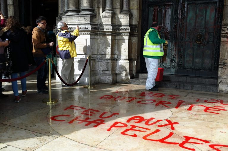 A worker cleans the graffiti at entrance  of the Sacre Coeur basilica in the Montmartre district of Paris, Wednesday, March 19, 2014. There were no immediate claims of responsibility for graffiti found at the iconic basilica. Graffiti on the floor reads: Down with any authority. (AP Photo/Thibault Camus)