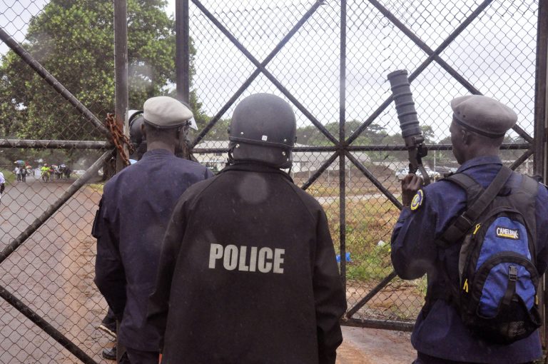 Liberian Police dressed in riot gear deploy at a MSF, 'Doctors Without Borders', Ebola treatment center, in the rain, as they provide security in the city of Monrovia, Liberia, Monday, Aug. 18, 2014. Liberia's armed forces were given orders to shoot people trying to illegally cross the border from neighboring Sierra Leone, which was closed to stem the spread of Ebola, local newspaper Daily Observer reported Monday. (AP Photo/Abbas Dulleh)