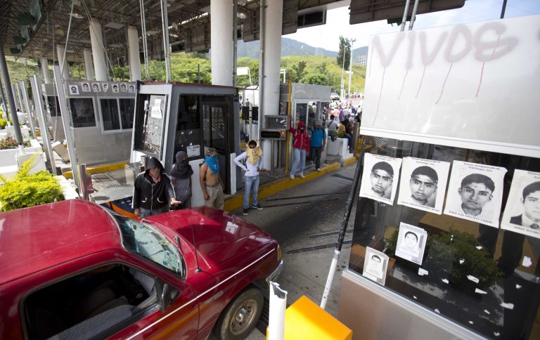 Masked student occupy a toll booth as students block a main highway to protest the disappearance of 43 missing college students in Chilpancingo, Mexico, Wednesday, Oct. 14, 2014. Mexican police expanded their search for the missing students Wednesday after investigators determined that 28 sets of human remains recovered from a mass grave were not those of any of the youths. (AP Photo/Eduardo Verdugo)