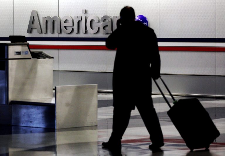 FILE - In this Tuesday, Nov. 29, 2011, file photo, a passenger walks through an American Airlines baggage claim area at O'Hare International Airport in Chicago. American and US Airways on Tuesday, April 8, 2014 announced changes to their policies on checked-bag fees and redeeming miles for free flights. Passengers traveling on American on miles they earned or who paid full price for an economy seat won't get to check two bags for free anymore. (AP Photo/Nam Y. Huh, File)
