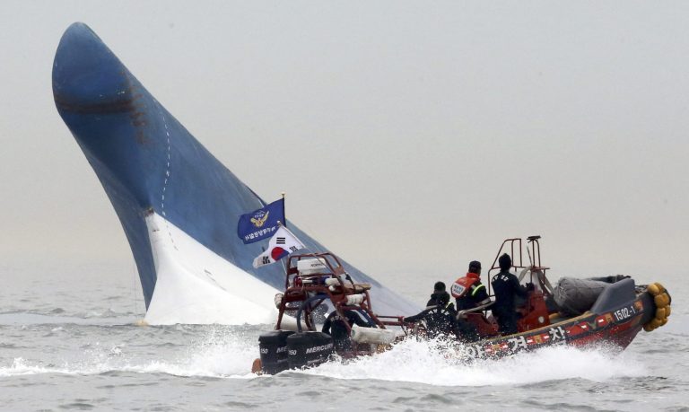 FILE - In this April 16, 2014 file photo, South Korean coast guard officers try to rescue passengers from the Sewol ferry as it sinks in the water off the southern coast near Jindo, south of Seoul, South Korea. The doomed ferry Sewol exceeded its cargo limit on 246 trips - nearly every voyage it made in which it reported cargo - in the 13 months before it sank, according to documents that reveal the regulatory failures that allowed passengers by the hundreds to set off on an unsafe vessel. And it may have been more overloaded than ever on its final journey. (AP Photo/Yonhap, File) KOREA OUT