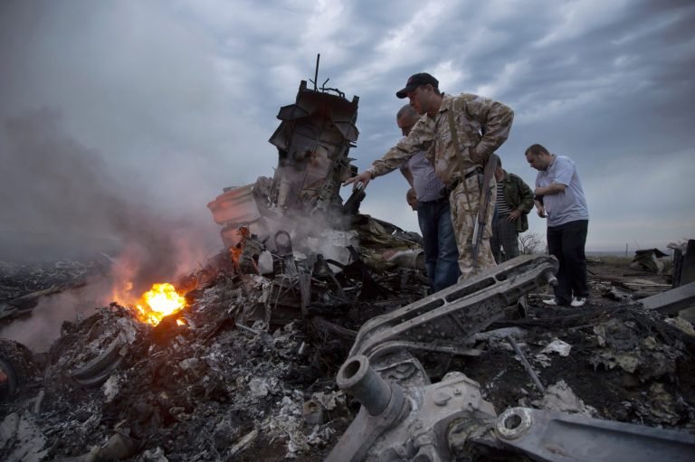FILE - In this July 17, 2014 file photo, people inspect the crash site of a passenger plane near the village of Hrabove, Ukraine. The downing of the jet could prove to be a turning point in the country's conflict. But which way it turns depends mainly on who carried out the attack and how convincingly it can be proved to the world. (AP Photo/Dmitry Lovetsky)