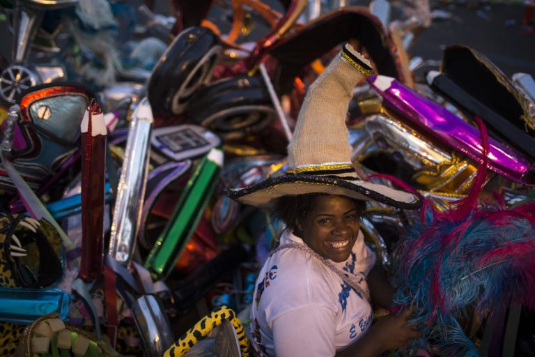 Elaine da Silva Moraes poses for a photo backdropped by piles of discarded costumes after carnival celebrations at the Sambadrome in Rio de Janeiro, Brazil, Tuesday, March 4, 2014. Moraes is a 