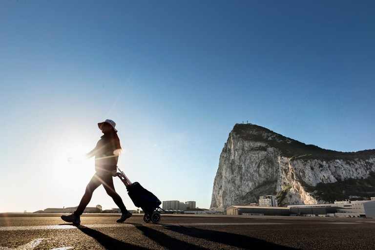 In this Wednesday, March 1, 2017 photo, a woman walks on the Spanish side of the border between Spain and the British overseas territory of Gibraltar with the Rock as a background, in La Linea de la Concepcion, Southern Spain. As Gibraltar braces itself to be dragged out of the European Union along with the United Kingdom, the livelihoods of nearly 300,000 people living in an economic region spanning two countries, have been thrown up in the air. (AP Photo/Daniel Ochoa de Olza)