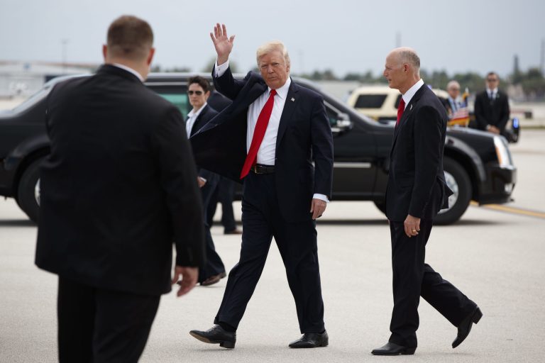 President Trump waves as he walks with Florida Gov. Rick Scott upon his arrival at Miami International Airport on Friday before speaking about Cuba policy. (AP Photo/Evan Vucci)
