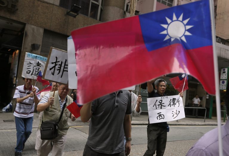Protesters raise Taiwanese flags and placards marching to Vietnam's consulate in Hong Kong, Thursday, May 15, 2014, to protest anti-China unrest in Vietnam. Mobs burned and looted scores of foreign-owned factories in Vietnam following a large protest by workers against China's recent placement of an oil rig in disputed Southeast Asian waters, officials said Wednesday. The Chinese words in the photo read 