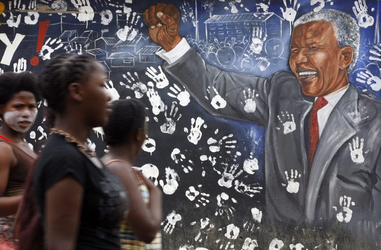   Young women walk pass a mural depicting former South African President Nelson Mandela at Alexandra township in Johannesburg, South Africa, Tuesday, Dec. 11, 2012. South Africa's presidency says former President Nelson Mandela is suffering from a recurring lung infection and is responding to treatment. The statement Tuesday, Dec. 11, 2012 from presidential spokesman Mac Maharaj said the 94-year-old anti-apartheid icon is 