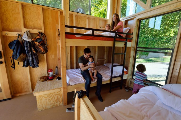 This July 24, 2014 photo released by California State Parks shows Cal Poly Pomona Architecture students Emily Williams, top, and Bryan Charney as they pose for photos with children in a cabin called The Wedge, one of four designs that Parks Forward proposes to put on hundreds of campsites throughout the California State Parks system, displayed at the State Fair Exhibit in Sacramento, Calif. Parks Forward, a group formed by the state to help revamp California's state parks, wants to open up their natural beauty to a wider array of people than typical campers by designing cabins to attract people to the parks who don't typically camp because they don't have expensive equipment, such as tents, or they don't want to sleep outside on the ground. (AP Photo/California State Parks, Brian Baer)