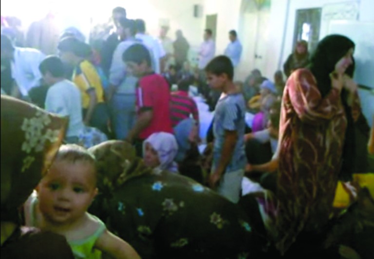 This image made from amateur video from Hama Revolution 2011 and accessed by AP video Friday, July 13, 2012 purports to show families gathered around bodies of victims killed by violence that, according to anti-regime activists, was carried out by government forces in Tremseh, Syria, about 15 kilometers (nine miles) northwest of the central city of Hama. Anti-regime activists in Syria said Friday that government gunners rained shells on a poor, farming village before armed thugs moved in, leaving scores of people dead in what rebels claim is one of the worst single days of bloodshed in the uprising against President Bashar Assad's regime. (AP Photo/ Hama Revolution 2011 via AP video)