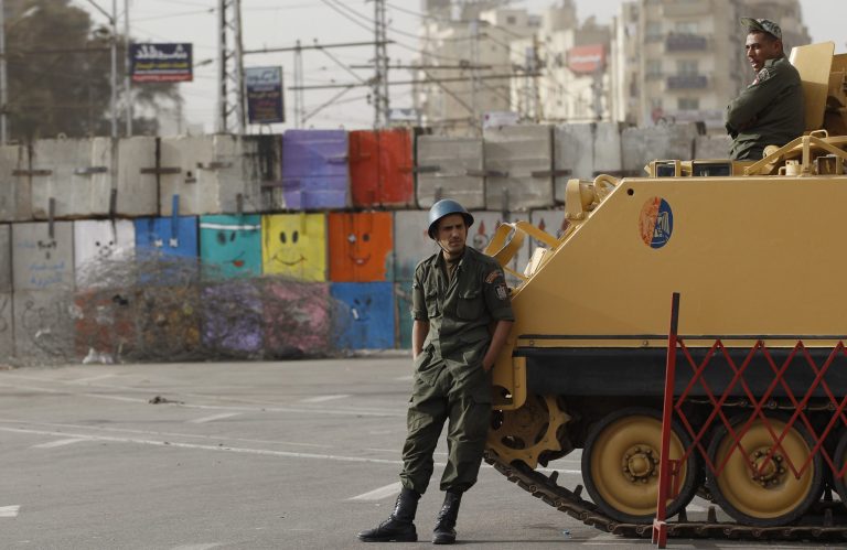   Soldiers stand guard by an armored vehicle in front of the Presidential Palace in Cairo, Egypt, Monday, Dec. 10, 2012. The Egyptian military on Monday assumed joint responsibility with the police for security and protecting state institutions until the results of a Dec. 15 constitutional referendum are announced. (AP Photo/Petr David Josek)  