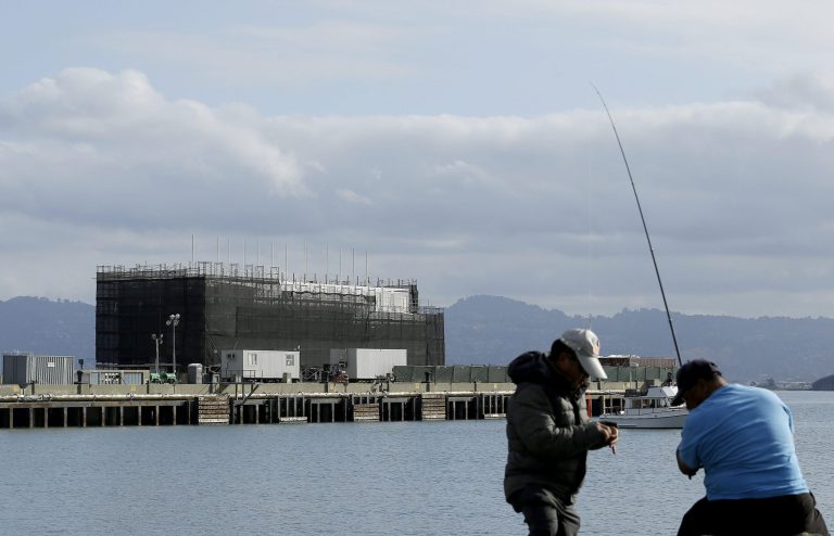 FILE - In this Tuesday, Oct. 29, 2013, file photo, two men fish in the water in front of a Google barge on Treasure Island in San Francisco. A state agency says Google must move its mystery barge from a construction site on an island in the middle of the San Francisco Bay because the permits are not in order. (AP Photo/Jeff Chiu, File)