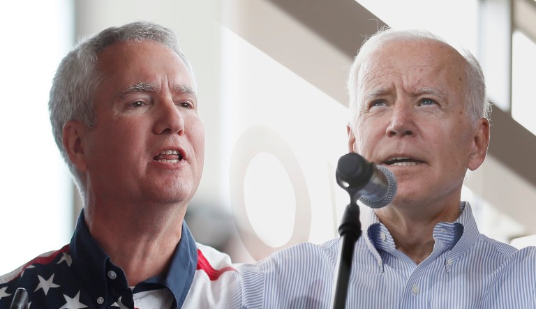 A man protests against Joe Biden (right) at a campaign stop in Iowa.