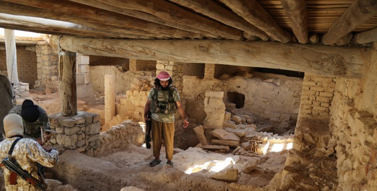 This picture released late Thursday, Aug. 20, 2015, by an Islamic State militant-affiliated website, shows Islamic State militants standing inside the ancient monastery of the Saint Eliane, near the town of Qaryatain which the Islamic State captured in early August, in Homs province, Syria. (Islamic State militant website via AP)