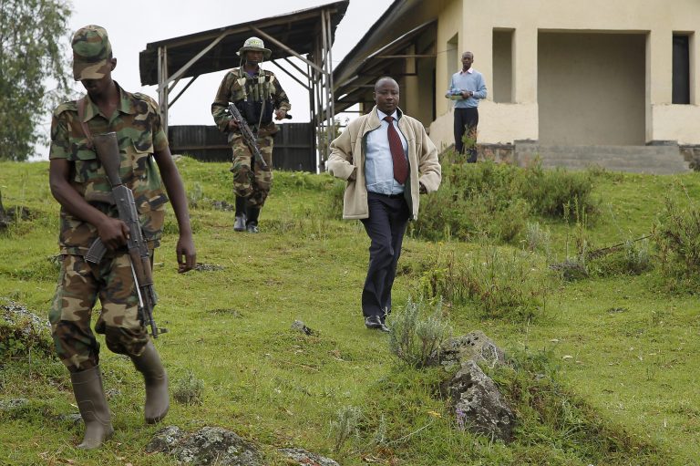   Congolese M23 rebel president Jean Marie Runiga walks with his security guards near the Congo-Uganda border town of Bunagana Wednesday Dec. 5 2012. Speaking to the Associated Press, Runiga said they would not accept for the Kinshasa government to pay the M23 expenses at the scheduled Kampala talks later this week, as the two are still in a belligerent state. M23 rebels completed their withdrawal from the strategic eastern city of Goma on Saturday, in compliance with an agreement reached between the rebel group and a regional body, they could still be seen in positions three kilometers from Goma airport. (AP Photo/Jerome Delay)  