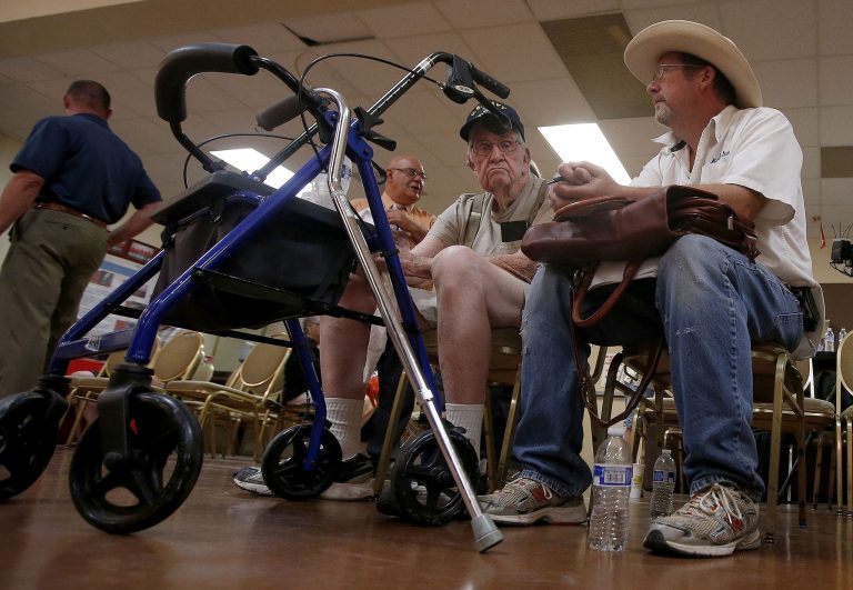 Don Parker, right, waits with his father, Harley Parker, center, a World War II veteran, on Tuesday as they wait their turn to speak with someone at a health care crisis center set up at the American Legion Post 1 hall in Phoenix. The FBI revealed on Wednesday that it had opened a criminal investigation into a Department of Veterans Affairs reeling from allegations of falsified records and inappropriate scheduling practices. (AP Photo/Ross D. Franklin, File)