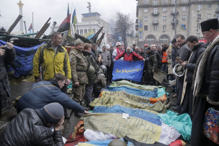 Activists and priests pay respects to protesters who were killed in clashes with police, a flag held by one activist reads 