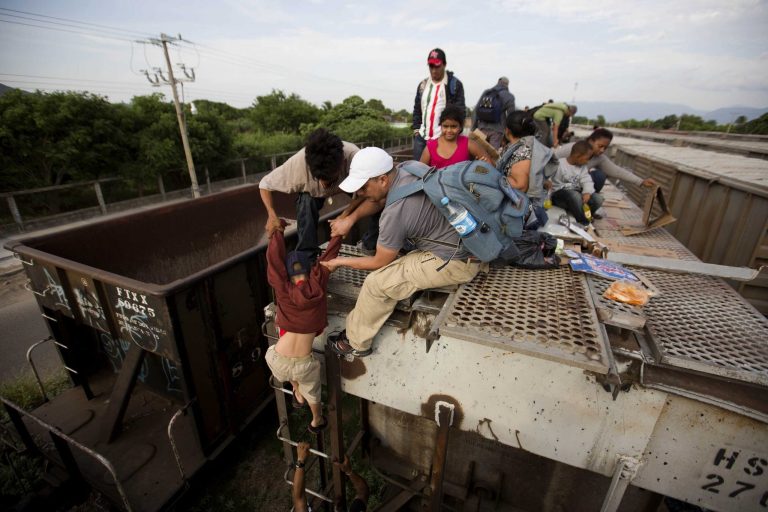 In this July 12, 2014, photo, a young boy is helped down from a freight car, as Central American migrants board a northbound freight train in Ixtepec, Mexico. Many smugglers take their charges from the southern Chiapas or Oaxaca states to Mexico City on La Bestia, the decrepit freight train, and from there, they choose one of three main routes: to Reynosa in Tamaulipas, Ciudad Juarez in Chihuahua, or cross the Sonoran desert to the outskirts of Mexicali. (AP Photo/Eduardo Verdugo)