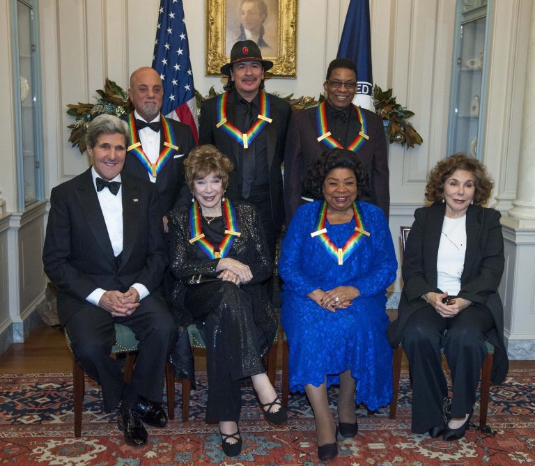 Secretary of State John Kerry, with the 2013 Kennedy Center honorees, from left, seated Shirley MacLain, and Martina Arroyo, along with Teresa Heinz Kerry. Standing are Billy Joel, Carlos Santana, and Herbie Hancock,  pose for a photo at the State Department for the Kennedy Center Honors gala dinner on Saturday, Dec. 7, 2013 in Washington. (AP Photo/Kevin Wolf)